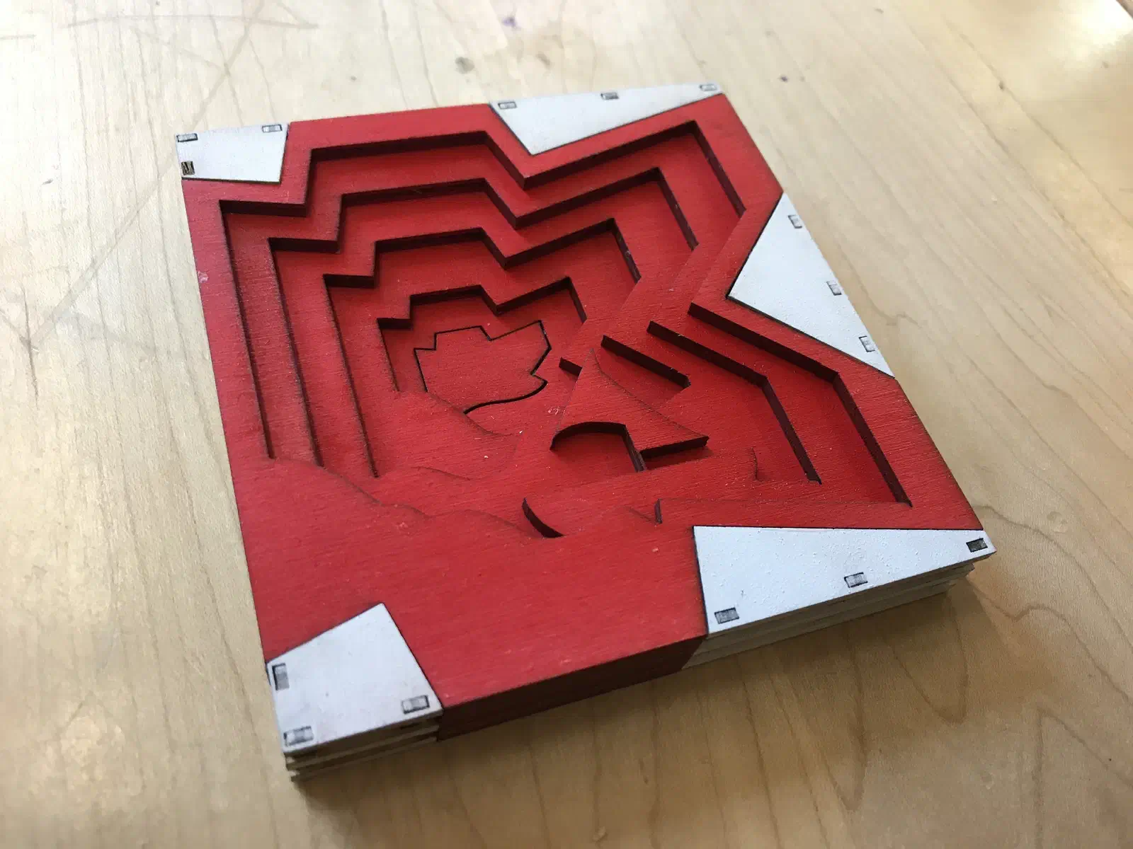 A red layered star shape carved in stepped levels, showing a city skyline in the negative space.