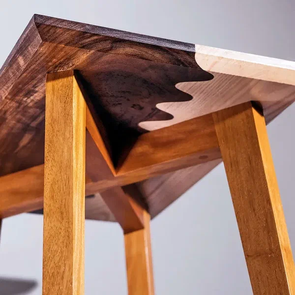 A side table with a two-tone wooden top joined by a wavy seam.