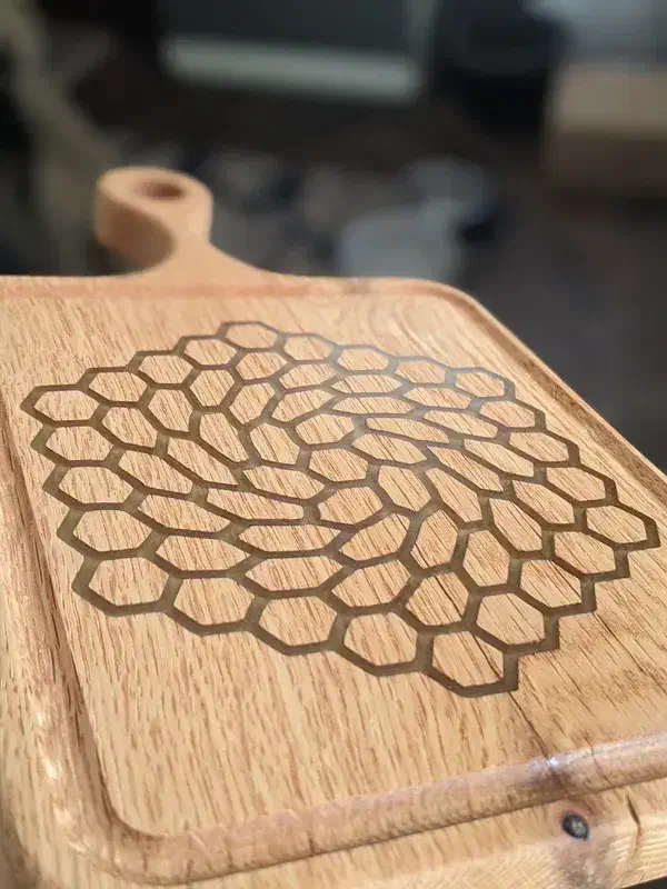 Close view of the swirling hexagon carve and beveled edge on a finished wooden board