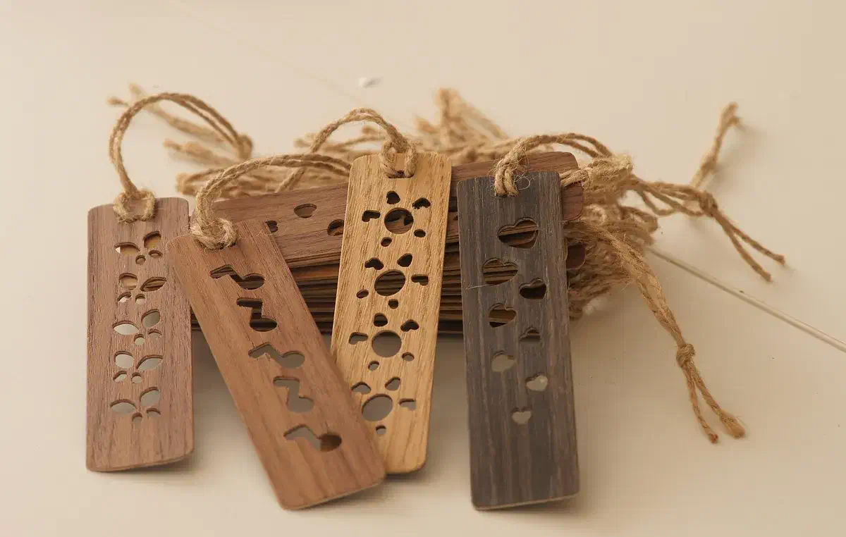 Finished brown and pale veneer bookmarks with cutout hearts, flowers and musical notes and cord tassels, arranged together on a pale background