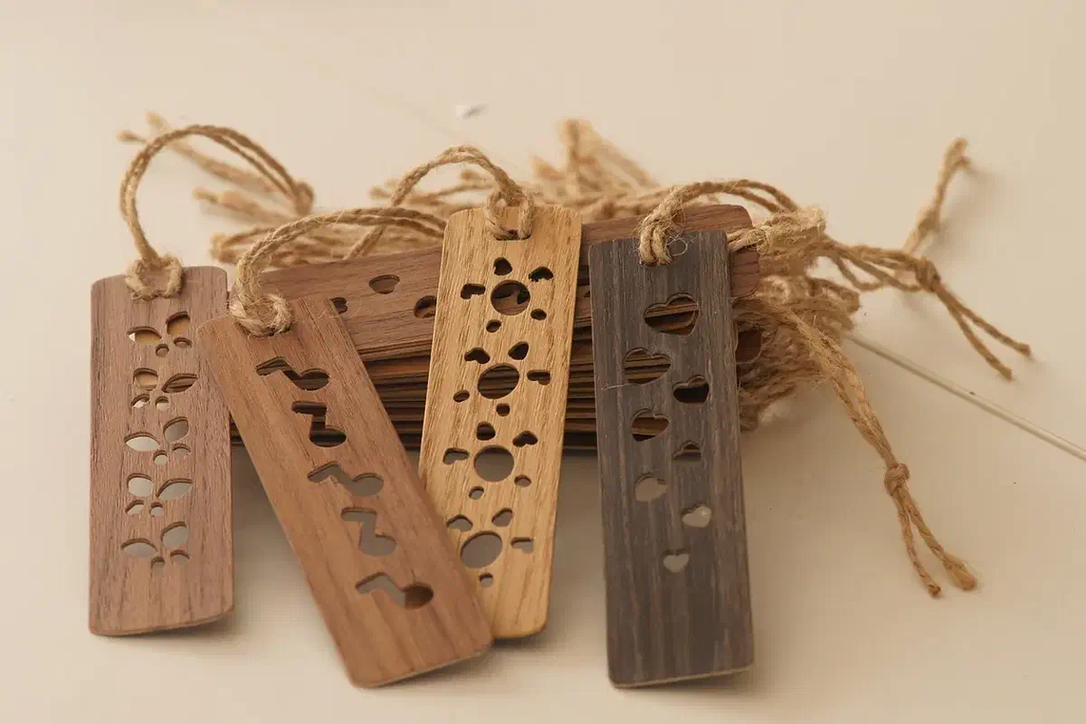 Finished brown and pale veneer bookmarks with cutout hearts, flowers and musical notes and cord tassels, arranged together on a pale background