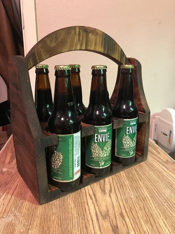 Finished dark wooden bottle tote holding six green-labeled bottles on a wooden tabletop