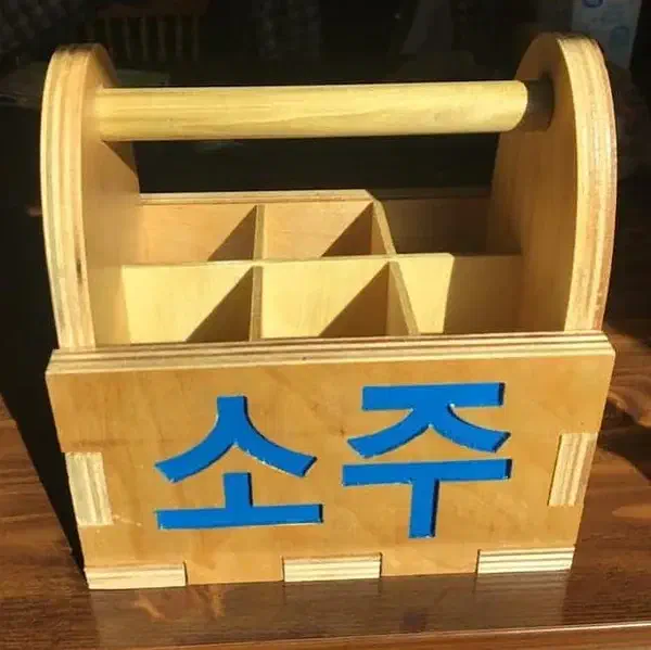 Finished plywood bottle tote with a round wooden dowel handle, divided compartments and blue Korean lettering