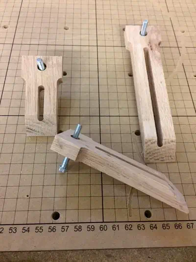 Three wooden slotted hold-down clamps of different lengths with threaded metal hardware