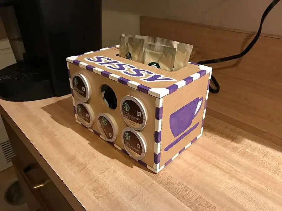 A finger-jointed wooden coffee pod box with purple painted details and flavor packets