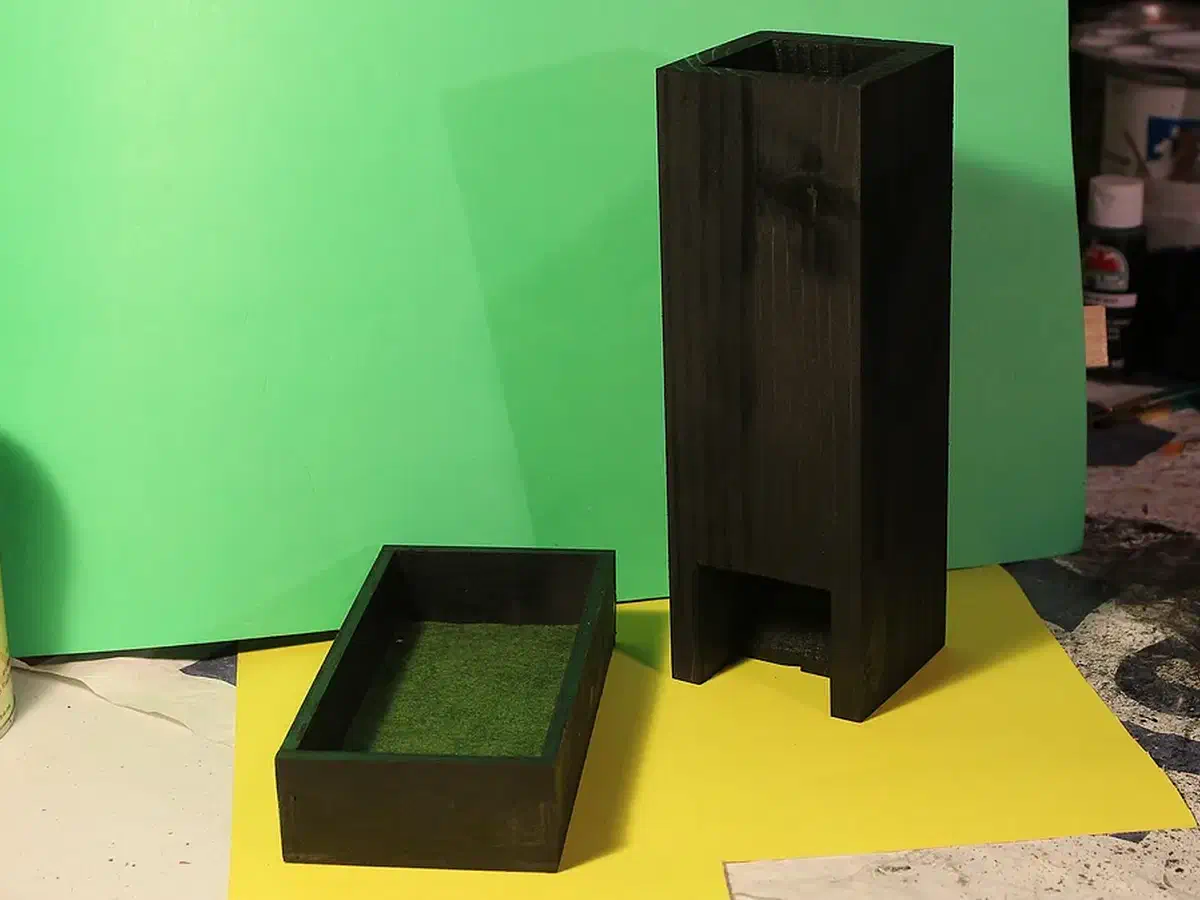 Black-finished wooden dice tower beside a shallow tray lined with green felt