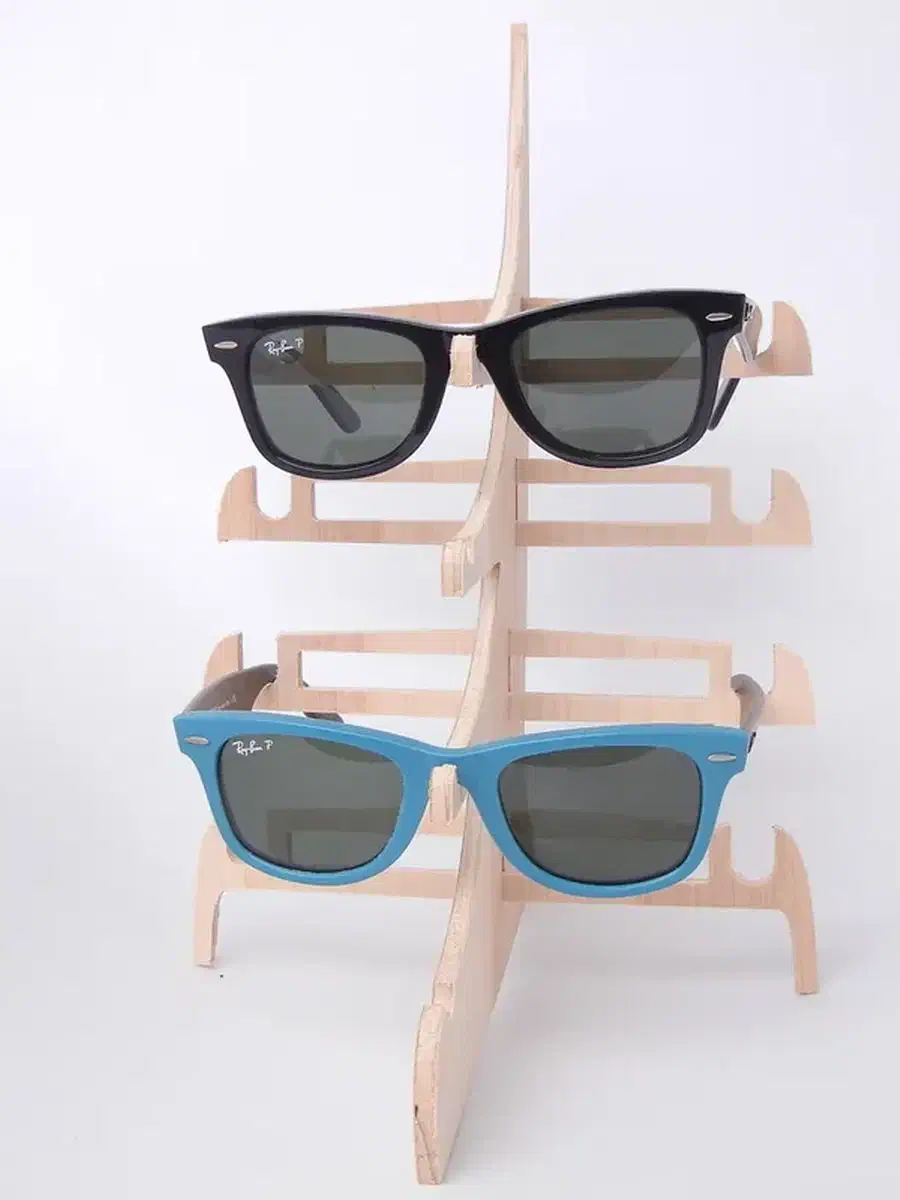 A pale wooden freestanding rack holding black and turquoise sunglasses
