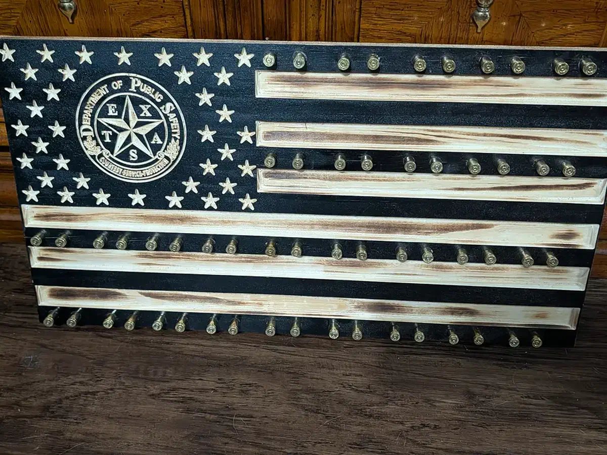 Black and natural-wood flag with challenge coins supported along rows of spent shell casings