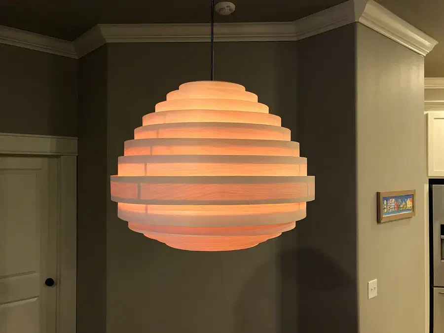 A finished maple veneer pendant lamp glowing warmly in a room