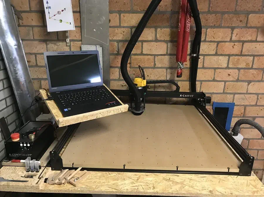 A laptop supported by a plywood pivoting arm attached beside an X-Carve