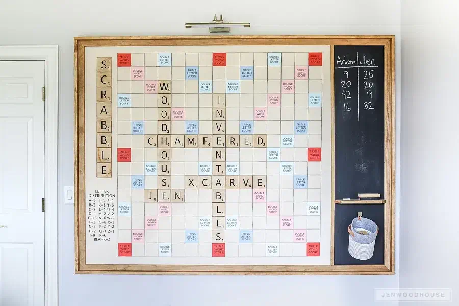 A large framed wall-mounted Scrabble game with wooden letter tiles, colored bonus squares and a black score panel