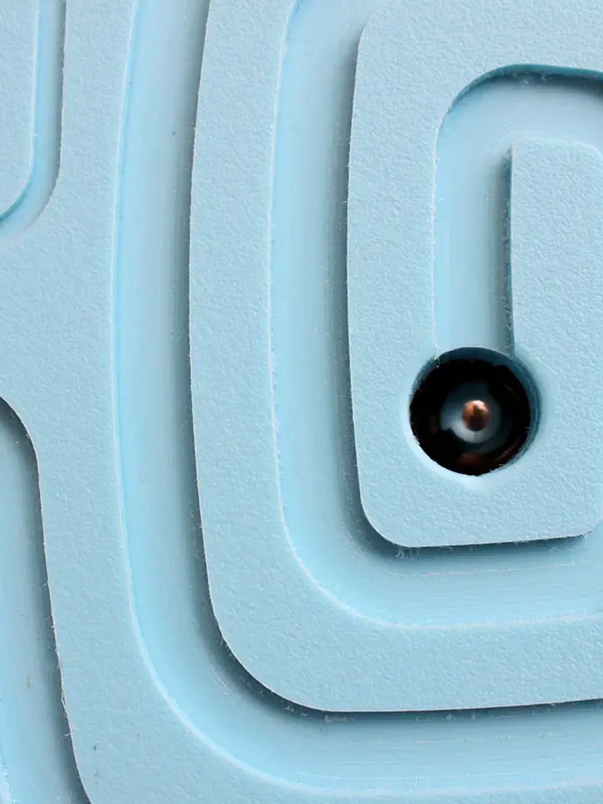 Close-up of a steel ball at the exit of a blue HDPE maze, with curved channels around it