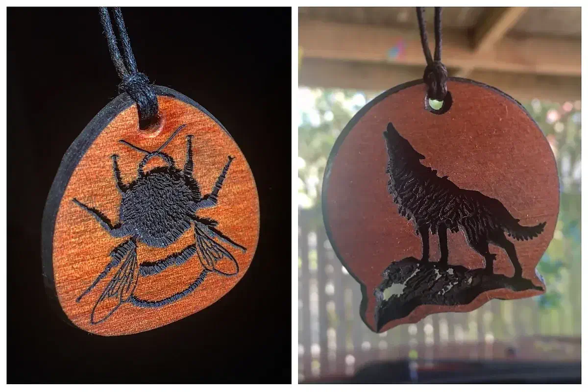 Two wooden pendants on dark cords, one with a black bee and one with a black wolf