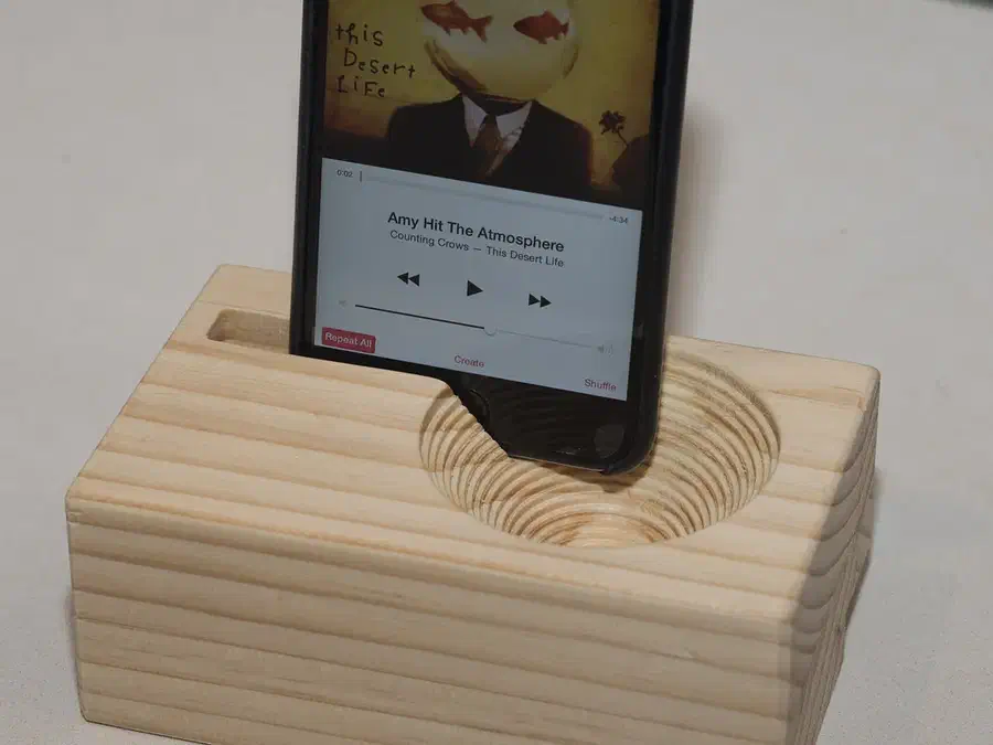 Phone standing in a wooden block with a stepped circular sound cavity