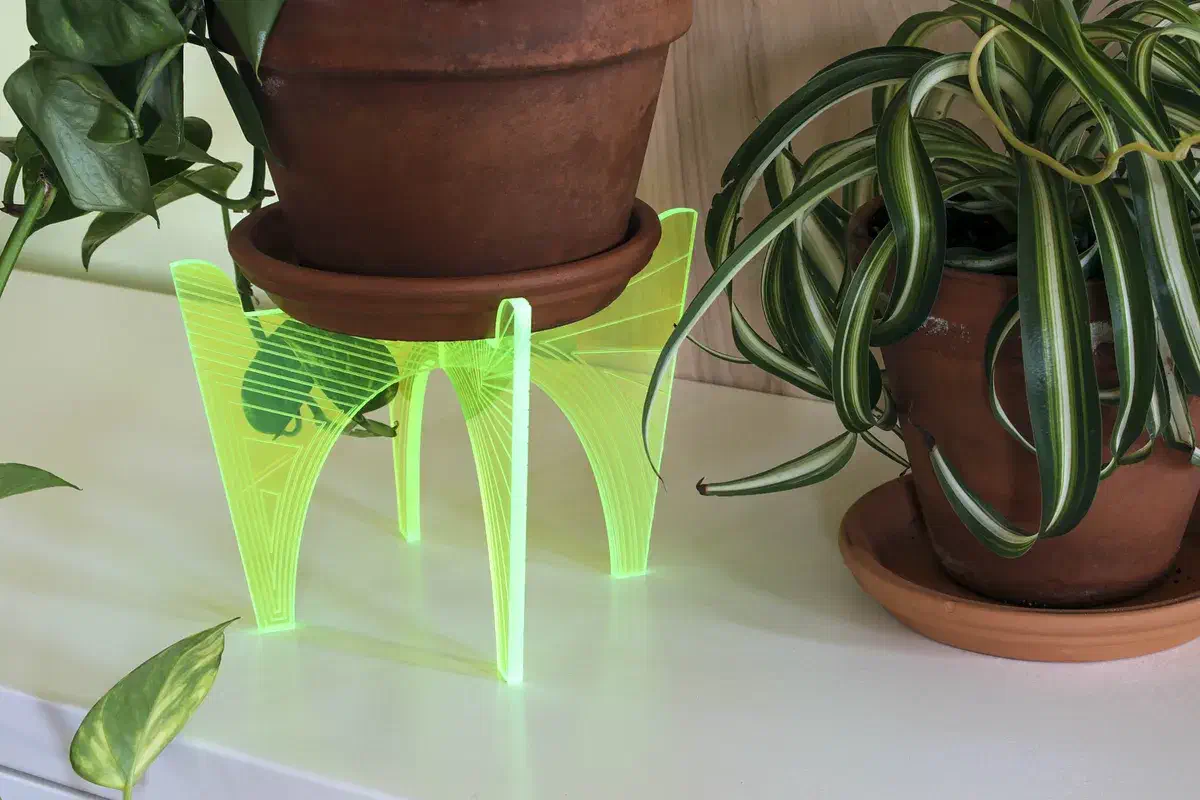 A terracotta plant pot on a neon yellow acrylic stand with engraved crossing lines