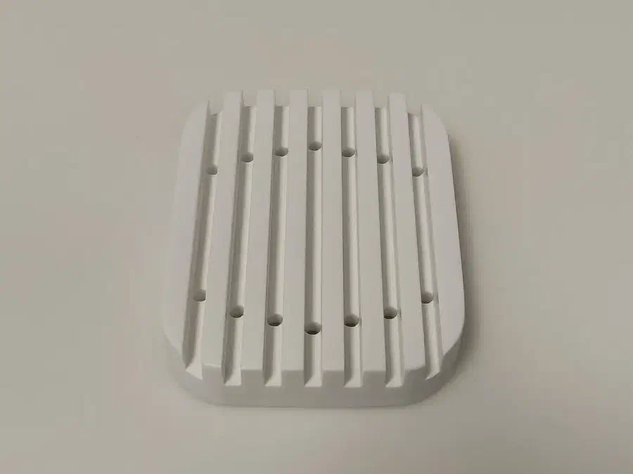 Top view of a finished white Corian soap dish with straight grooves and small drainage holes