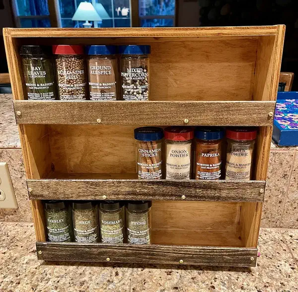 Allan Schwartz’s complete three-row wooden spice rack on a counter, with jars behind three dark front rails.