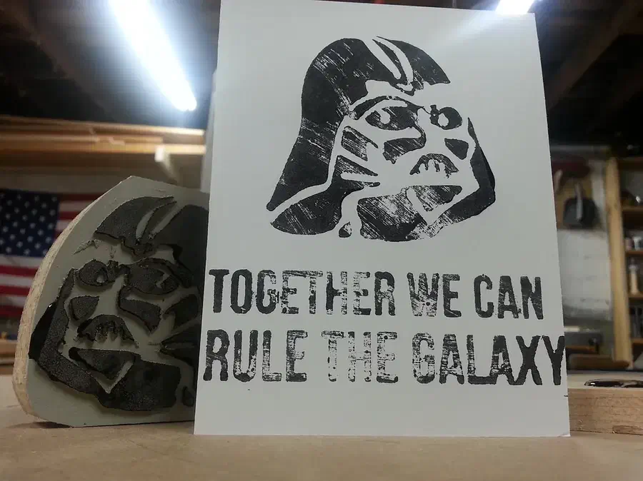 A white greeting card printed with a dark helmet portrait and the words Together we can rule the galaxy, beside the carved stamp