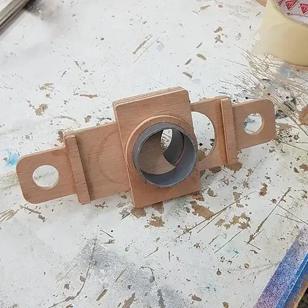 A finished plywood sliding blast gate with a gray pipe collar and extended shutter handle