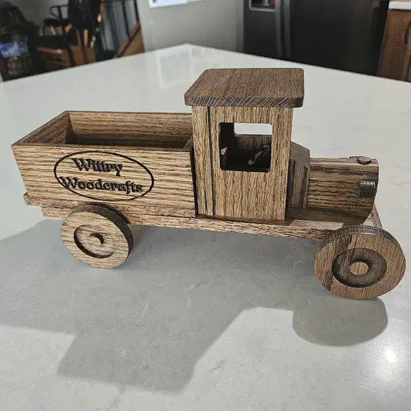 An unpainted wooden pickup truck with an open cargo bed, wood wheels and a logo on its side