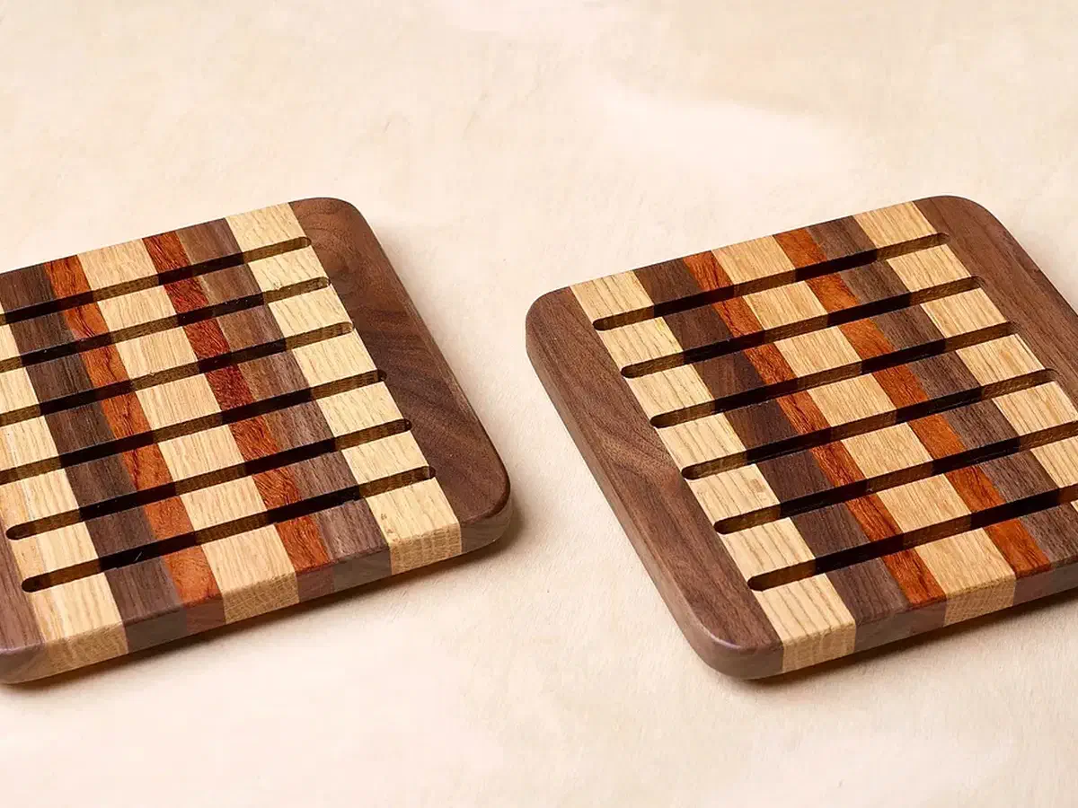 Striped scrap-wood trivets with parallel slots and rounded corners