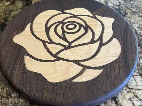 Round dark wooden trivet with a pale rose inlay