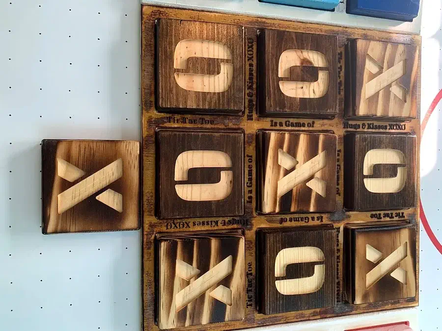 A wooden tic-tac-toe board filled with large square tiles carrying raised X and O shapes