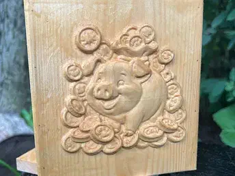 A smiling pig surrounded by clouds carved in relief into a wood panel